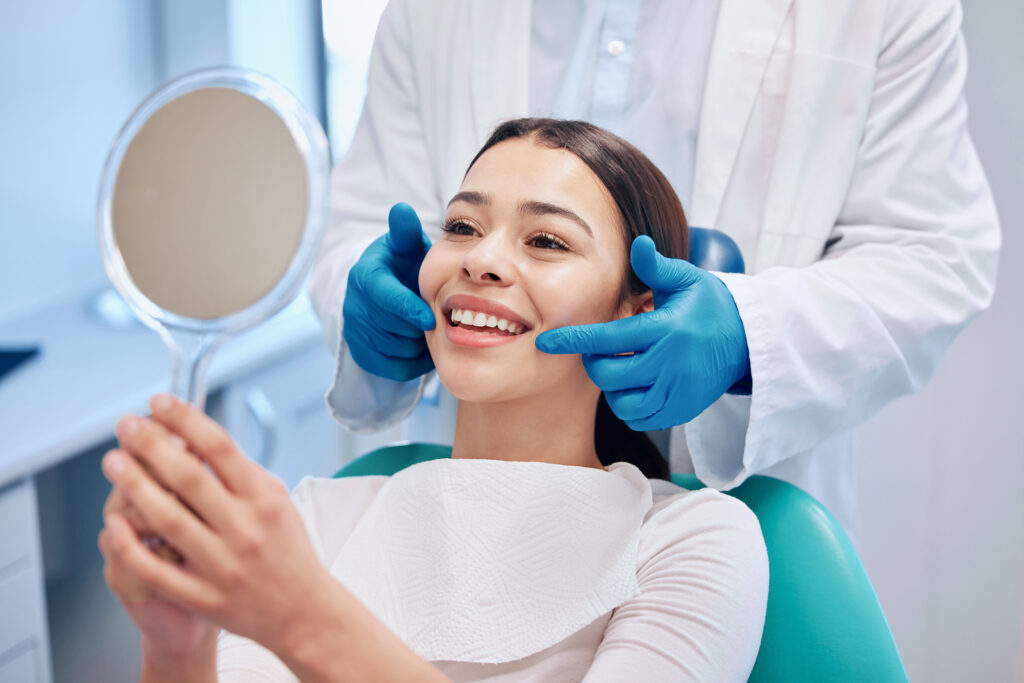 A young, hispanic woman checks her smile after oral surgery